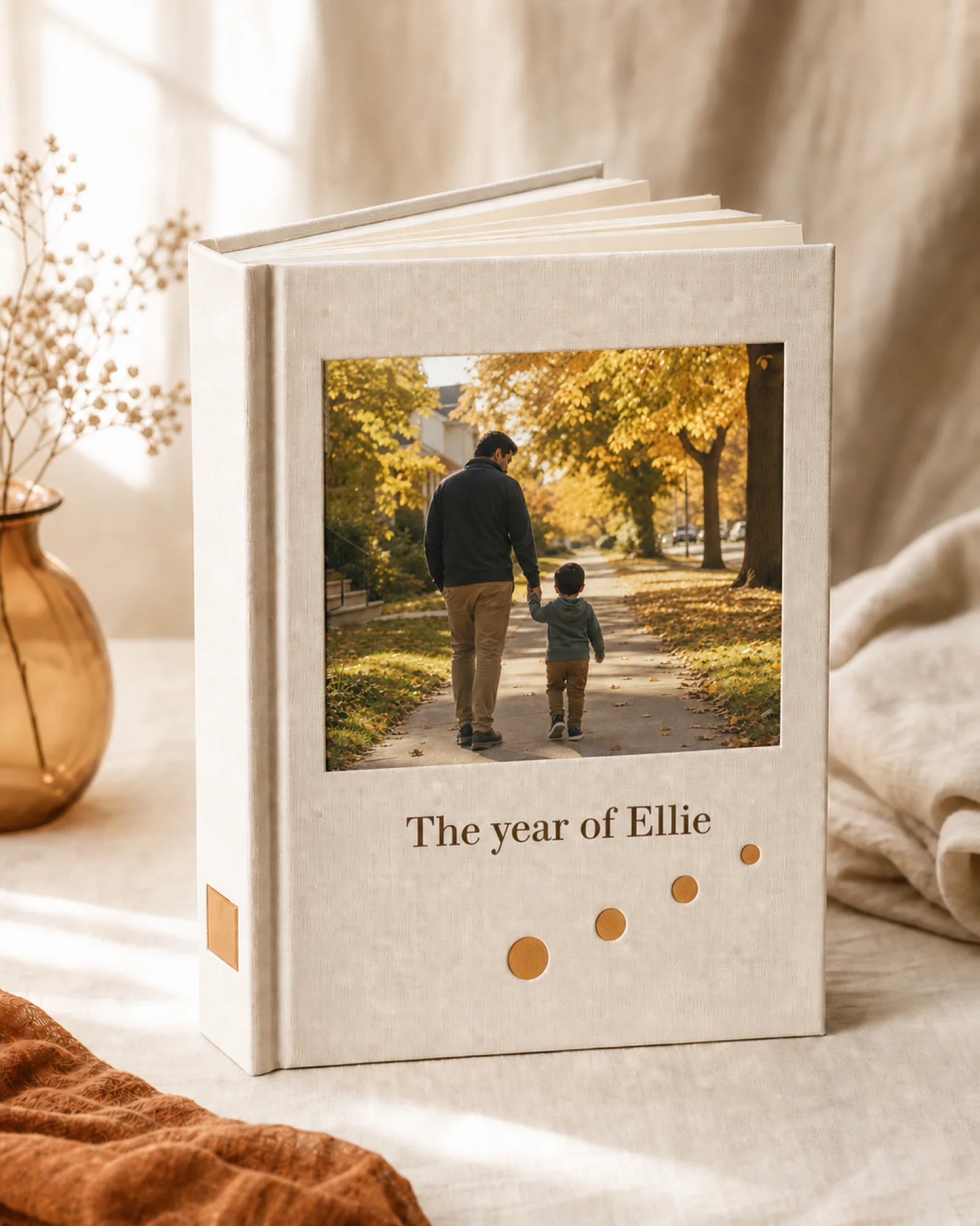 A cream linen-bound family yearbook with a parent and child walking away together on the cover